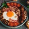 Traditional English breakfast, scrambled eggs, bacon, mushrooms, sausage, beans and cherry tomatoes on a rustic plank table.