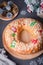 Traditional Epiphany cake Roscon de Reyes on grey stone table top with small Christmas tree and decoration closeup, top view