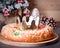 Traditional Epiphany cake Roscon de Reyes on wooden table top with small Christmas tree, wrapped gifts and decoration closeup, top