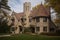 traditional exterior of tudor-style house, complete with turret, cast stone columns and decorative half-timbering