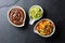 Traditional famous mexican sauces chocolate chili mole poblano, avocado guacamole and salsa pico del gallo on slate gray