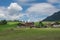 Traditional farm building in the German Alps surrounded by mountains, green hills, blue sky and clouds