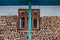 Traditional farmhouse wall decorated with firewood, green pillar and clothesline