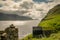 Traditional faroese shed ath the edge of the cliff, Mikladalur, Kalsoy, beautiful view on the sea and islands Kunoy and Bordoy,