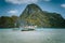 Traditional filippino banca boat in blue tropical lagoon at El Nido bay. Impressive karst mountains of Cadlao Island in