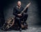 Traditional folk musician dressed in vintage Celtic clothes sits on a wooden box and plays mandolin.