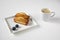 Traditional French financier cake - dessert concept - pastries and a cup of coffee in white ceramic dishes on a white table - side