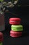 Traditional French macarons with pistachio, raspberry, currant cream on a dark background