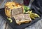 Traditional French pate en croute with goose liver with gherkin and pepperoni on a modern design cast iron tray