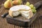 Traditional French soft cheese cremoulin with green grapes and yellow pears on a rustic wooden cutting board