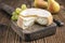 Traditional French soft cheese cremoulin with green grapes and yellow pears on a rustic wooden cutting board