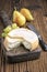 Traditional French soft cheese cremoulin with green grapes and yellow pears on a rustic wooden cutting board