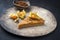 Traditional French Tarte au citron piece with orange and physalis fruit on a modern design plate