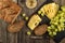 Traditional freshly baked bread with seeds, served with slices of cheese, grape and white wine on a wooden background