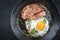 Traditional fried Allgauer veal roast roll sausage slices with fried egg in a  skillet with spices
