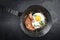 Traditional fried Allgauer veal roast roll sausage slices with fried egg in a skillet with spices on a black