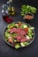 Traditional fried dry aged bison beef rump steak slices with vegetable, lettuce and mustard dressing on a Nordic design plate