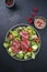 Traditional fried dry aged bison beef rump steak slices with vegetable, lettuce and mustard dressing on a Nordic design plate