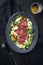 Traditional fried dry aged bison beef rump steak slices with vegetable, lettuce and mustard dressing on a Nordic design plate