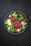 Traditional fried dry aged bison beef rump steak slices with vegetable, lettuce and parmesan cheese in a Nordic design plate