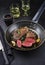 Traditional fried dry aged bison beef rump steaks with herbs and garlic in a rustic metal skillet