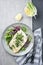 Traditional fried skrei coalfish filet served with mixed lettuce and herbs on a design plate