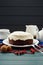 Traditional fruit cake minimalist style. Tasty chocolate cake with cream cheese and white teaware on dark blue background