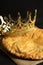 Traditional galette des Rois with decorative crown on black table, closeup