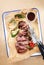 Traditional German barbecue sliced rostbraten with fried mushrooms and paprika on backing paper in a skillet