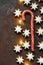 Traditional German Christmas Cookies Home Baked Glazed Cinnamon Stars with Nuts Candy Cane Garland Lights on Rusty Dark Background