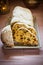 Traditional German Christmas stollen with raisins, nuts, candied fruits, sliced, powdered on plate, festive table setting, lit can