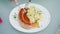 Traditional German food plate: grilled sausages and braised cabbage on a white plate. Woman`s hands with fork and knife