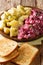 Traditional German red herring salad with garnish of boiled potatoes close-up in a plate. vertical