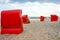 Traditional German roofed wicker beach chairs on the beach of Baltic Sea. Beach with red chairs on stormy sunny day. Ostsee
