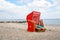 Traditional German roofed wicker beach chairs on the beach of Baltic Sea. Beach with red chairs on stormy sunny day. Ostsee