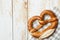 Traditional German savory lye pretzel with salt on checkered cotton kitchen towel on white plank wood table. Poster banner
