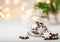 Traditional German star shaped cinnamon almond cookies with icing in cloche dome bell glass jar on white table. Lit candle