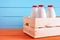 Traditional glass milk bottles in a wooden crate on orange wooden country kitchen table