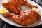 Traditional glazed sticky chicken leg quarters served with lemon closeup on a plate. horizontal