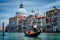 Traditional Gondola and gondolier on Canal Grande with Basilica di Santa Maria della Salute in the background in Venice