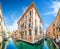 Traditional Gondolas on narrow canal between colorful houses, Venice, Italy