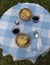 Traditional gratin onion soup dishes. Top view of a rustic table with blue squared tablecloth and ceramic plates with glasses of