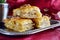 Traditional Greek baklava made with filo dough, sugar syrup and wallnuts on a metal tray with metal coffee cup on a