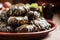 Traditional Greek dolma with meat in grape leaves, yogurt sauce, grapes and red wine on a clay dish, selective focus