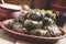 Traditional Greek dolma with meat in grape leaves, yogurt sauce, grapes and red wine on a clay dish, selective focus