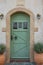 Traditional Greek house facade with white washed walls, green wooden door and flower pot in Chora, Kythira island, Greece