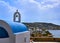 Traditional Greek Orthodox church, blue dome, bell tower overlooking typical Greek island landscape at summer day. Green