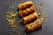 Traditional greek pastries saragli with pistachios on dark background