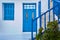 Traditional Greek porch, whitewashed walls, blue shutters, doorway and doors, banisters of street stairs. Mediterranean