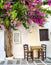 Traditional greek tavern cafe restaurant under a beautiful flower tree, cycladic islands, village serifos table and chairs in